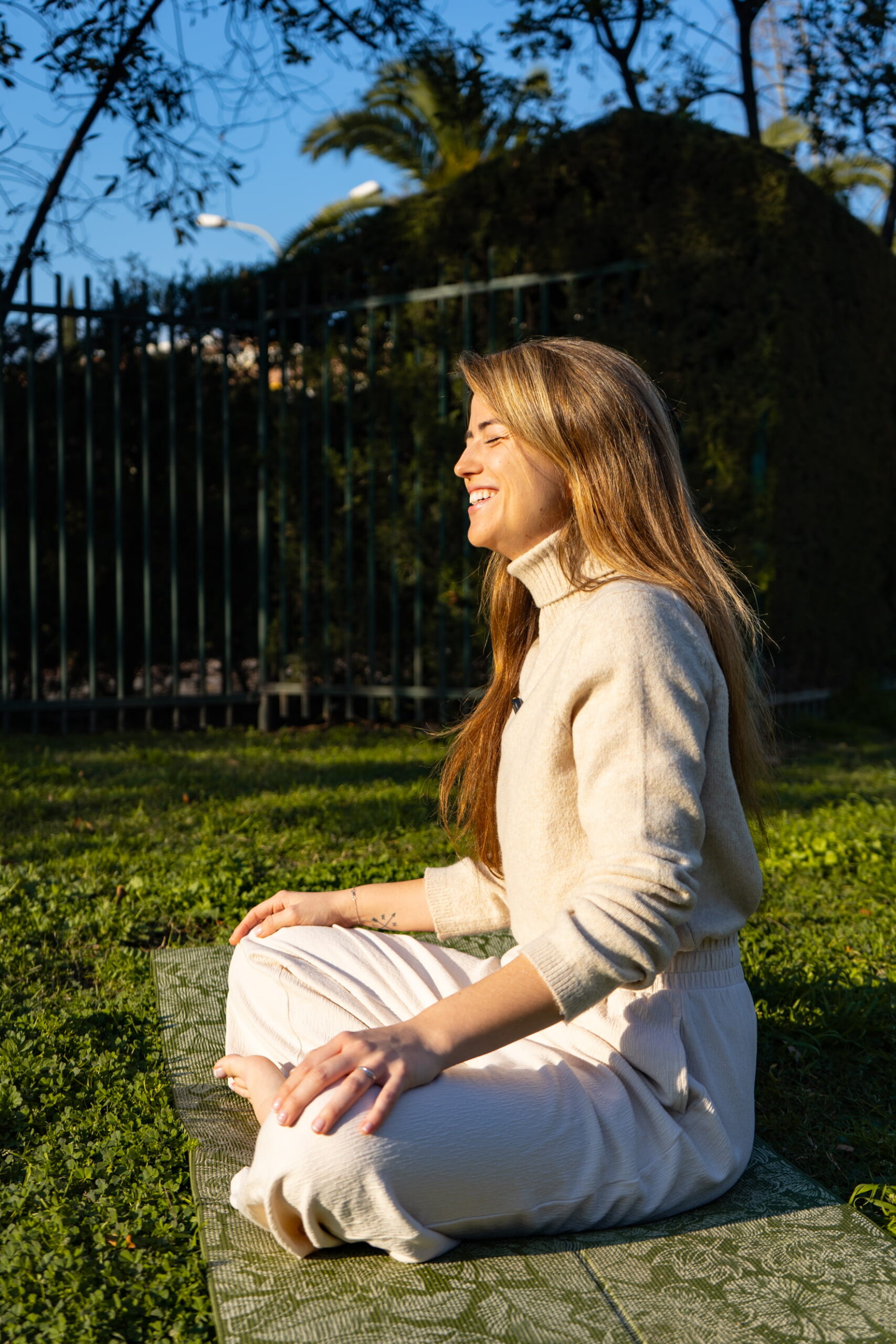 claudia sentada e iluminada por el sol practicando yoga en un Barcelona